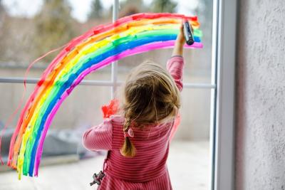 Child painting a rainbow on a window