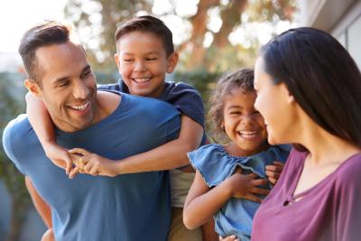 Man giving youth a piggy back ride and woman hold child