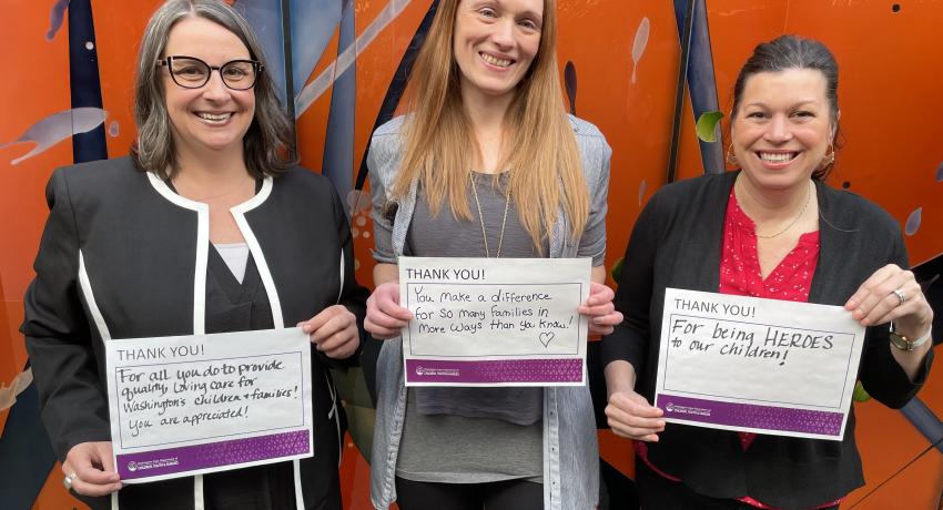 Three women with smiles holding up "Thank You" notes.