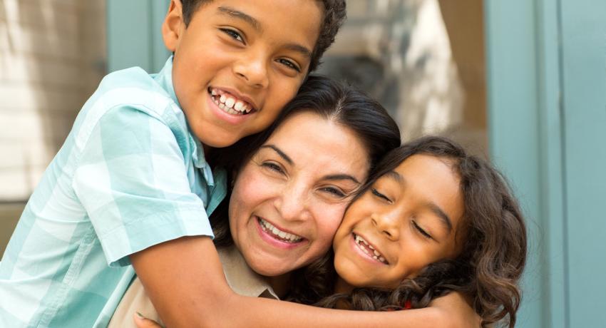 Woman and two children in an embrace.