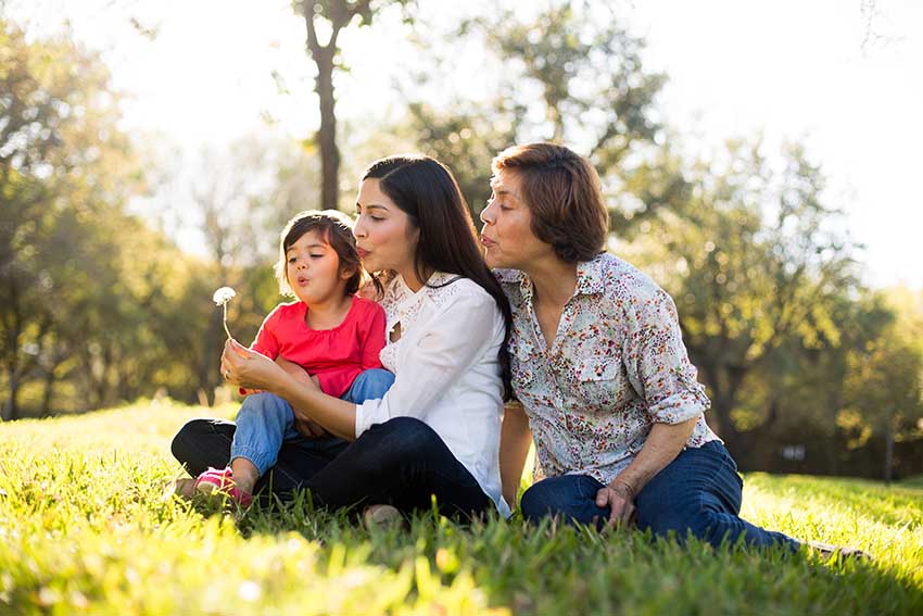 child, mother, and grandmother sitting on grass