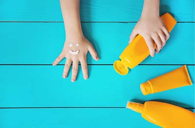 childs hands with bottles of sunscreen