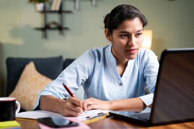 Woman looking at computer while taking notes