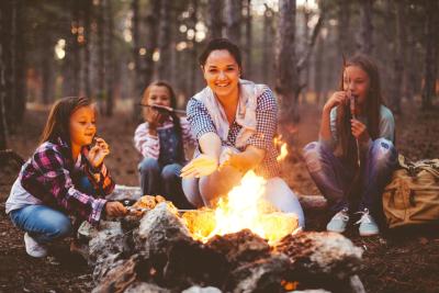 Adult and kids cooking hot dogs over a campfire