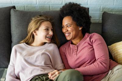 Teen girl and adult woman itting on couch and smiling at each other