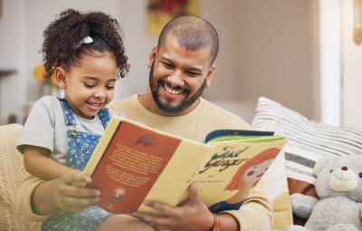 Adultand child smiling reading a book together