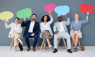 Five people sitting in chairs holing up talk bubbles to represent giving their feedback