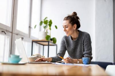 woman smiling at the computer with coffee and plant in the background