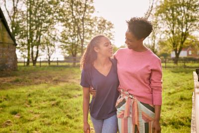 Adult and teen embracing and smiling at each other outside