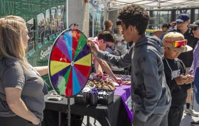 Youth spinning a game wheel at park event.
