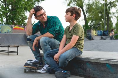 Adult male with young boy at skateboarding park.