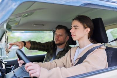 Adult teaching youth to drive