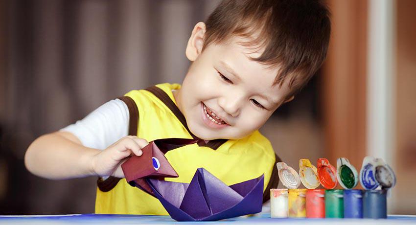Young boy playing with paper boat