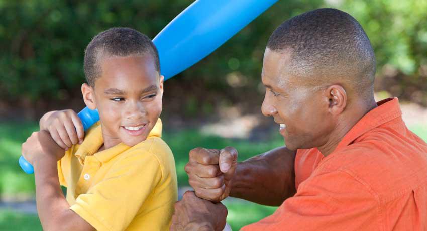 man teaching boy with bat