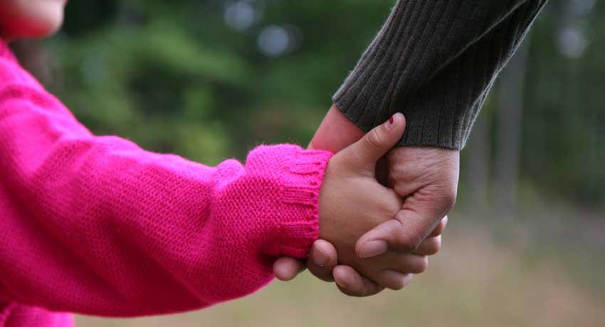 Adult hand holding childs hand