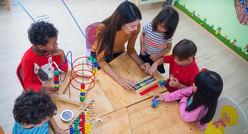 Teacher with students doing activities around a table