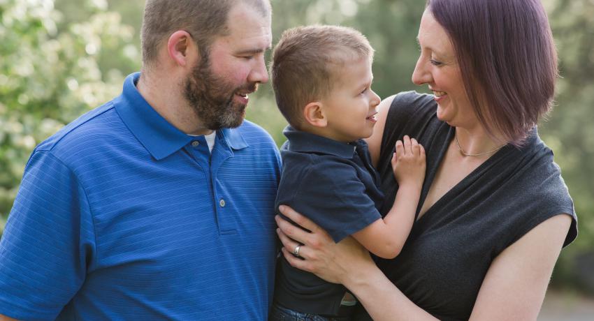 Little boy smiling with his adoptive parents. 