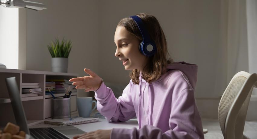 Youth participating in virtual learning smiling at her laptop.