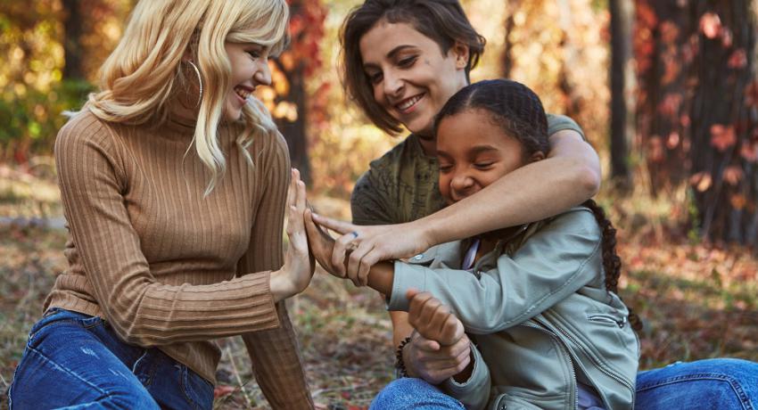 Happy couple sitting in nature with their adoptive daughter. 