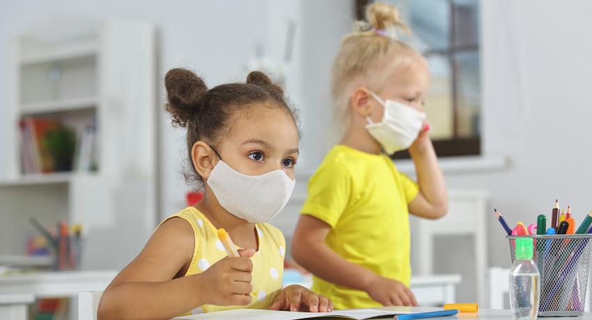 two young girls in child care wearing face masks