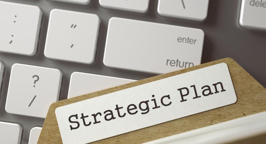 Strategic plan file resting on computer keyboard. 