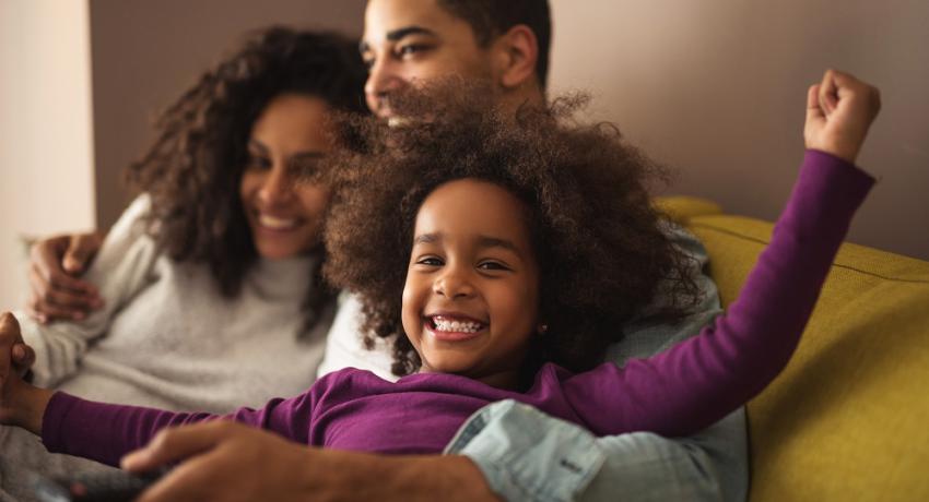 Happy family sitting on couch smiling. 