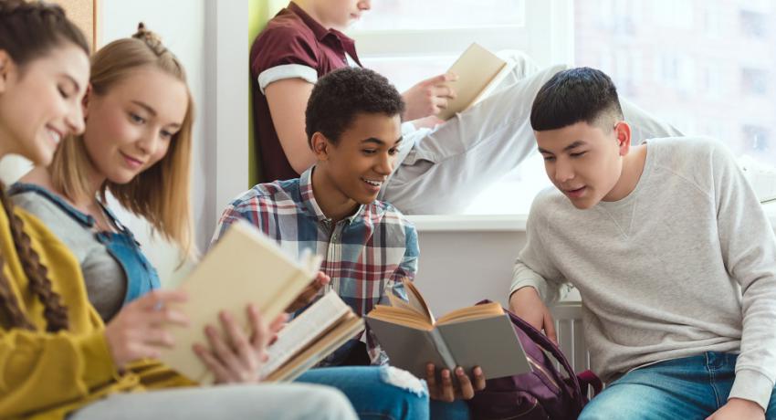 Group of young people hanging out in a library reading books together. 