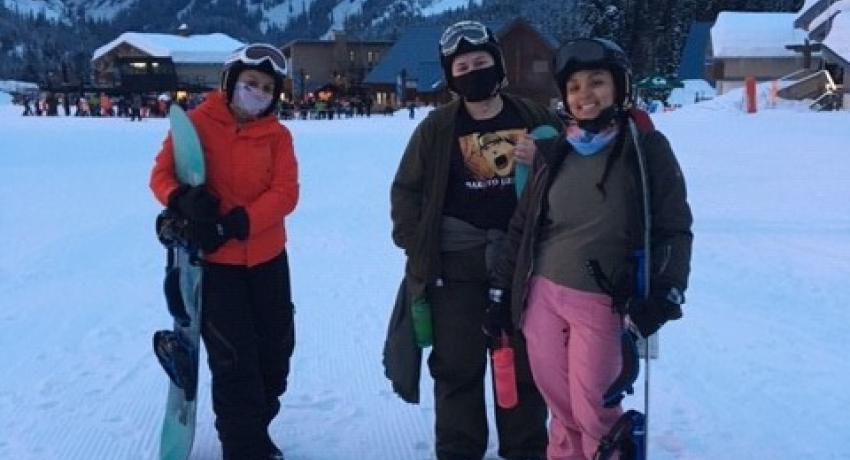 Ridgeview youth standing in the snow with their snowboarding gear in hand. 