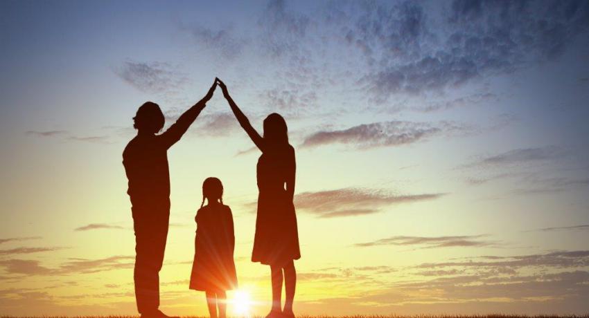 Silhouetted adults bridge their arms over a child. 