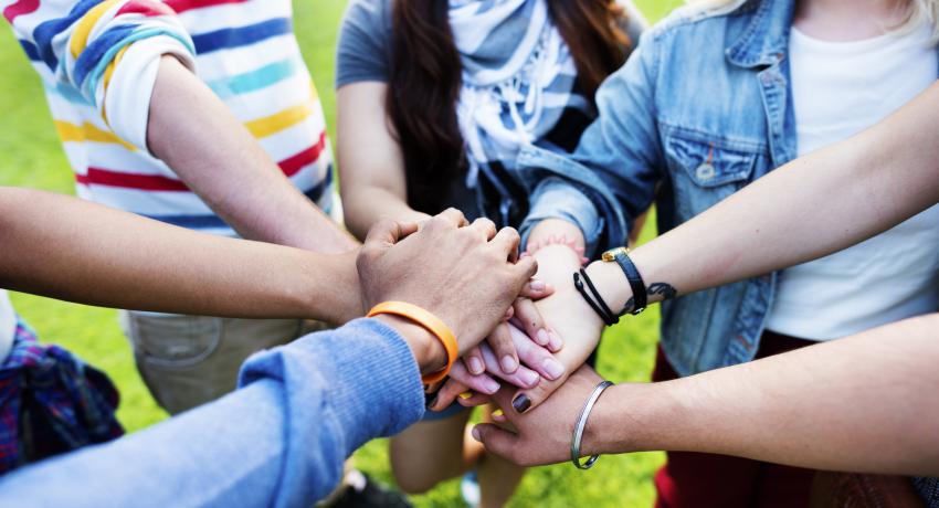 Young people put their hands together symbolizing unity. 