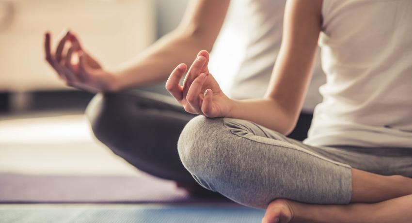 Two people sitting in a yoga pose. 