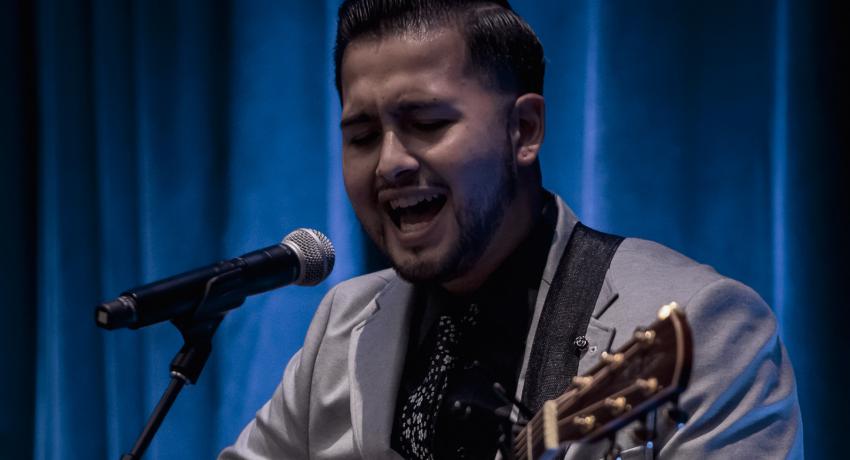 Tim singing an original song on stage at an awards ceremony. 