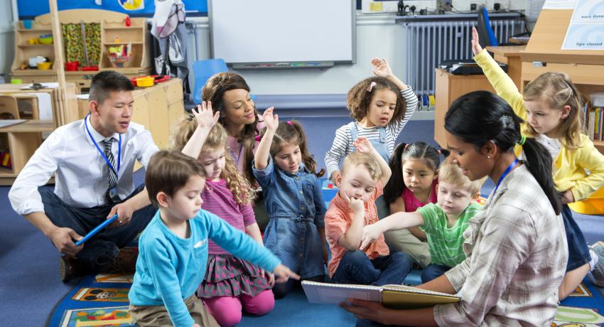 group of teachers with group of young children reading