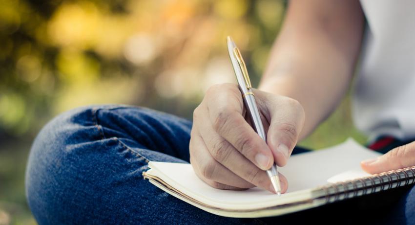 Young person writing in a journal in outdoor setting