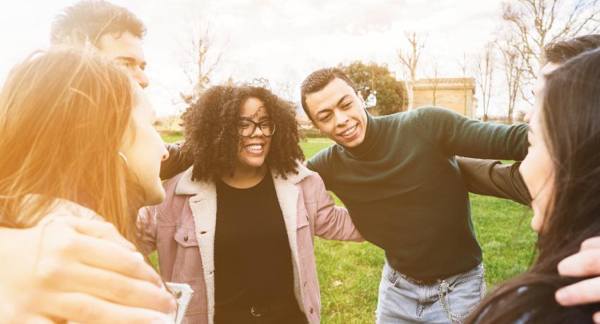 Young people huddling and smiling outdoors