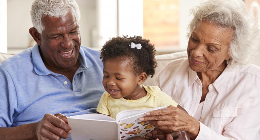 grandparents with child reading a book