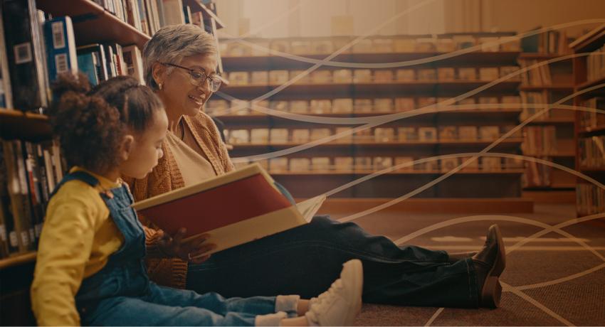 older adult reading to young child on the floor of a library