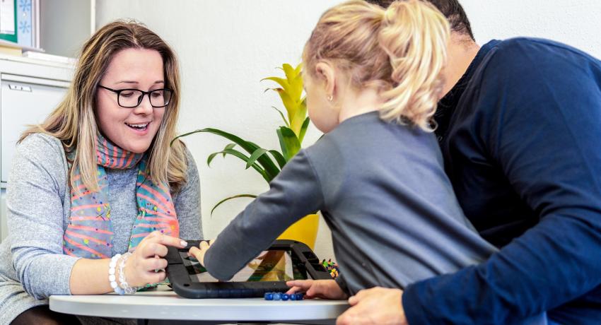 caseworker interacting over tablet with child and their father