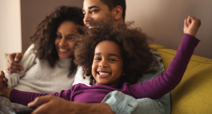 Family sitting together on a couch, smiling. 