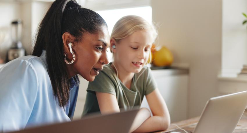 Woman and preteen sitting together looking at a laptop